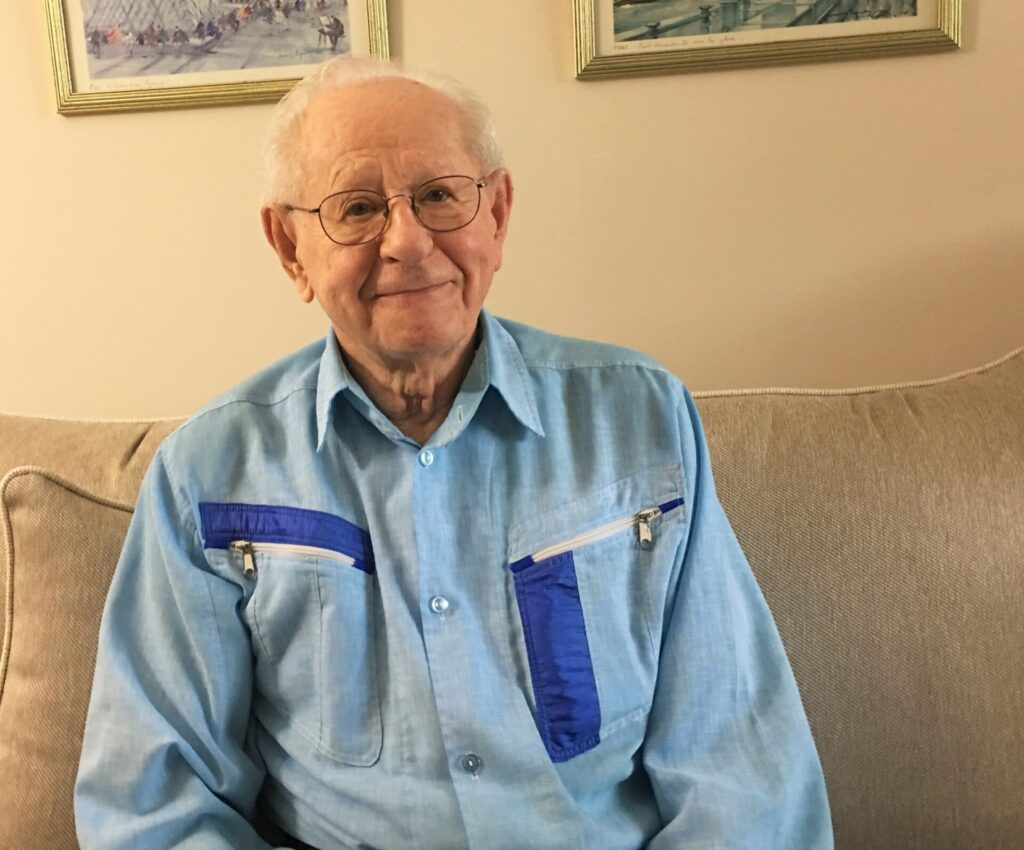 Elderly man smiling indoors wearing tie