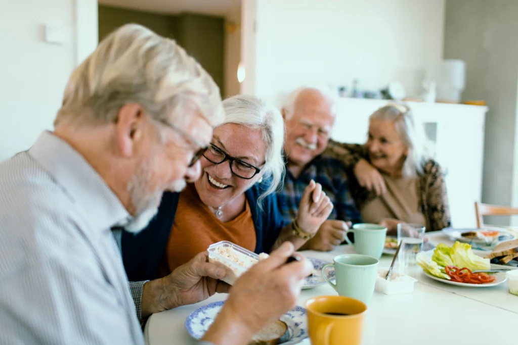 Group of a happy senior friends eating breakfast together at kitchen table